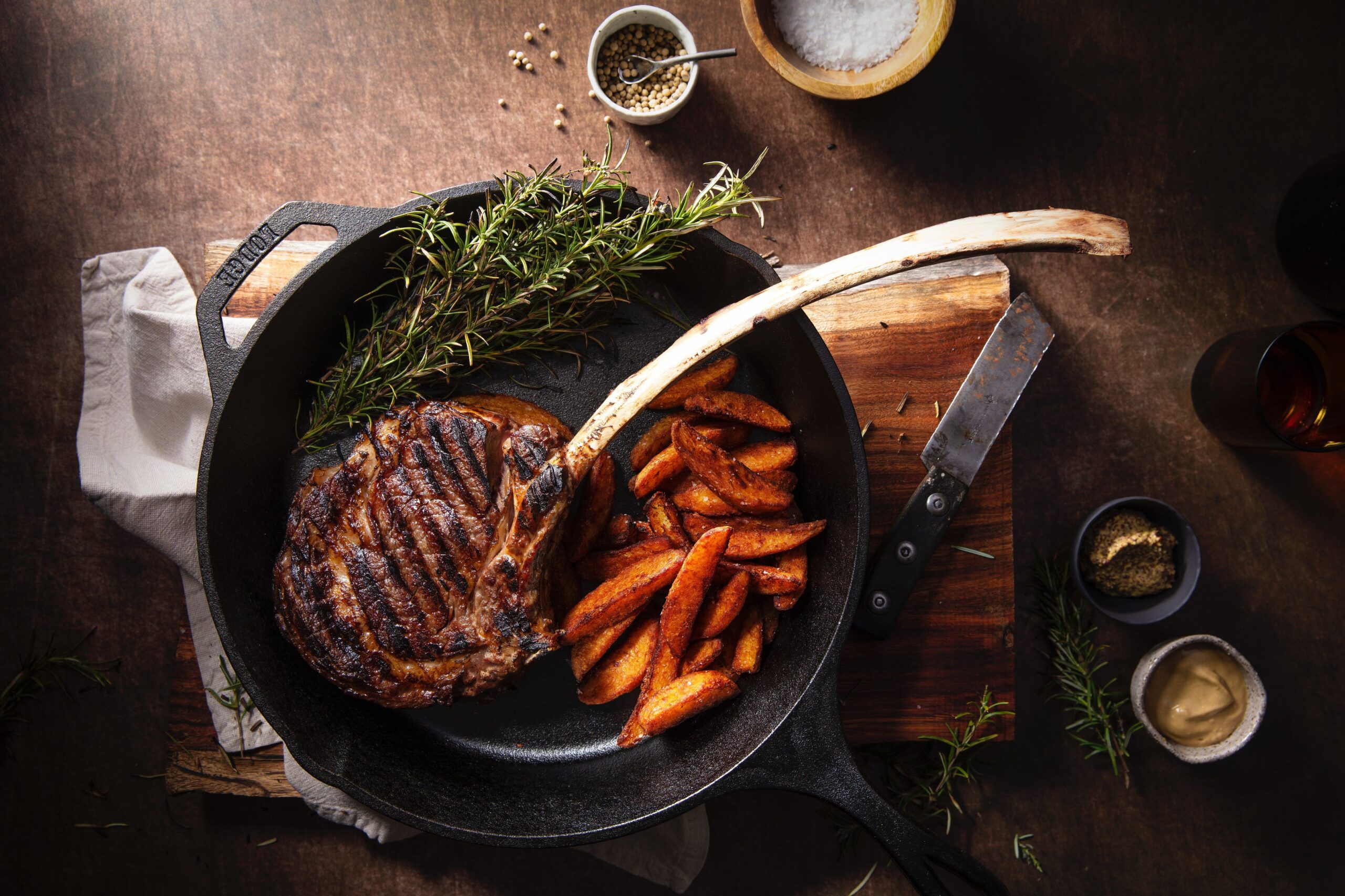 iron-skillet-with-meat-and-potatoes-on-wooden-board